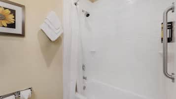 Ein Badezimmer mit Dusche, einem gerahmten Blumenbild an der Wand und einem Handtuchhalter mit Handtüchern.