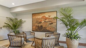 A modern living room with a large painting, comfortable seating, and potted plants. - Best Western Plus Plaza by the Green (Kent)