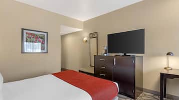 Una habitación de hotel con cama, televisión, cómoda y un cuadro en la pared.