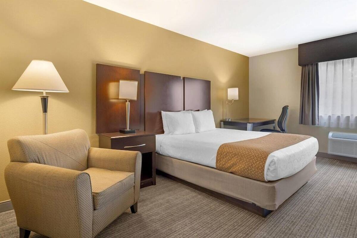 Een hotelkamer met een bed, een stoel, een bureau en een lamp.