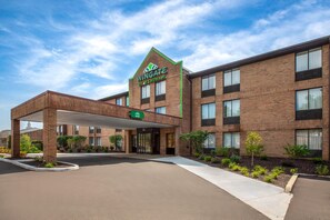A Wingate by Wyndham hotel with a brick facade, a covered entrance, and a clear sky. - Wingate by Wyndham Livonia (Livonia)