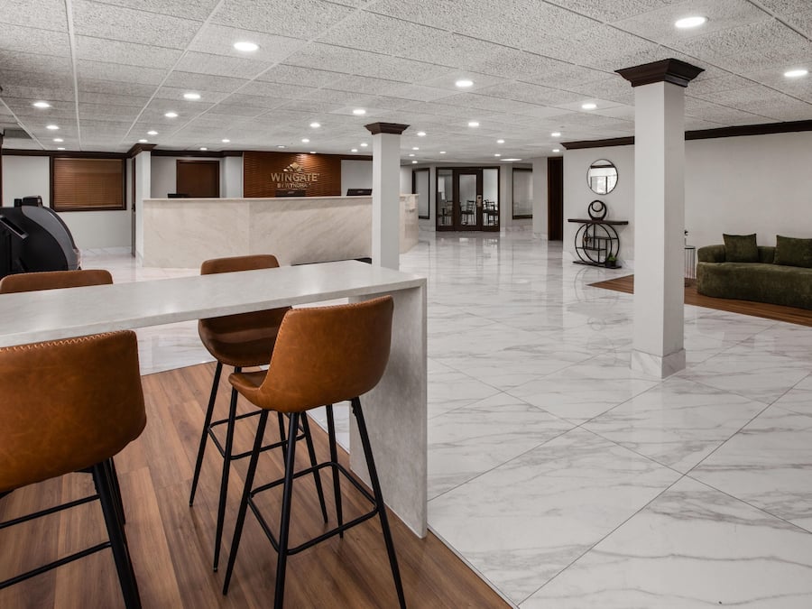 A modern reception area with a marble counter, wooden flooring, and a green sofa in the background.