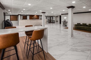 Una moderna zona de recepción con mostrador de mármol, suelo de madera y un sofá verde al fondo.