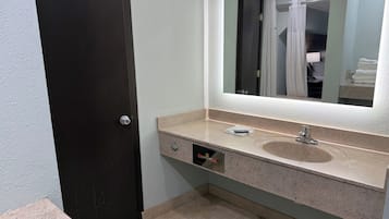 Une salle de bain avec une porte sombre, un lavabo avec un miroir et un porte-serviettes.
