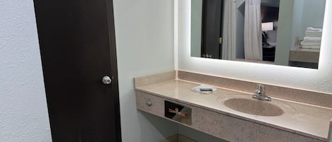 A bathroom with a dark door, a sink with a mirror, and a towel rack.