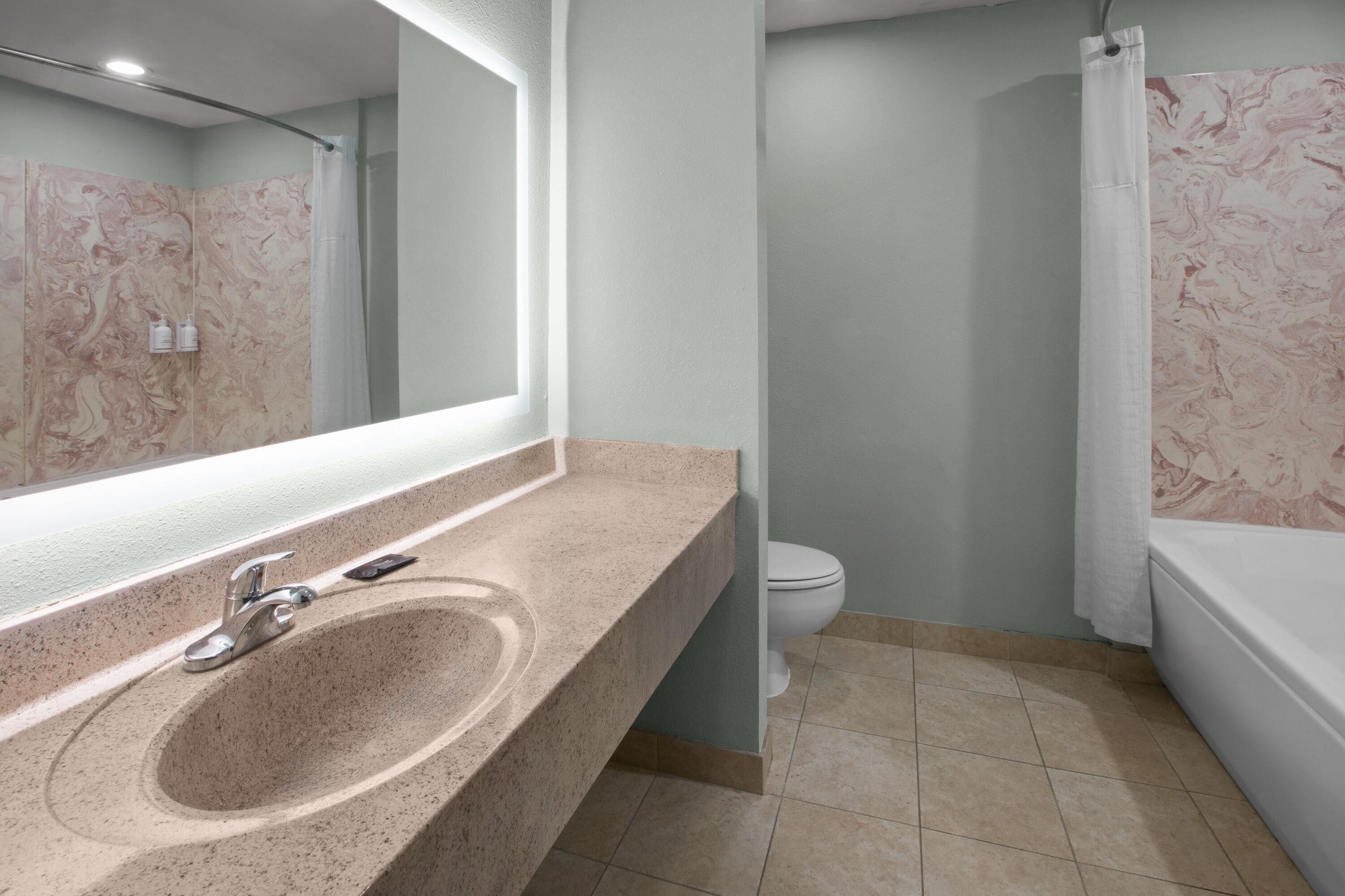 A bathroom with a marble sink, a toilet, and a bathtub.