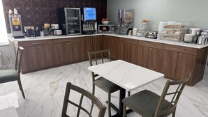 Eine moderne Küche mit Marmorarbeitsplatte, einer Kaffeemaschine, einer Mikrowelle und einem Kühlschrank.