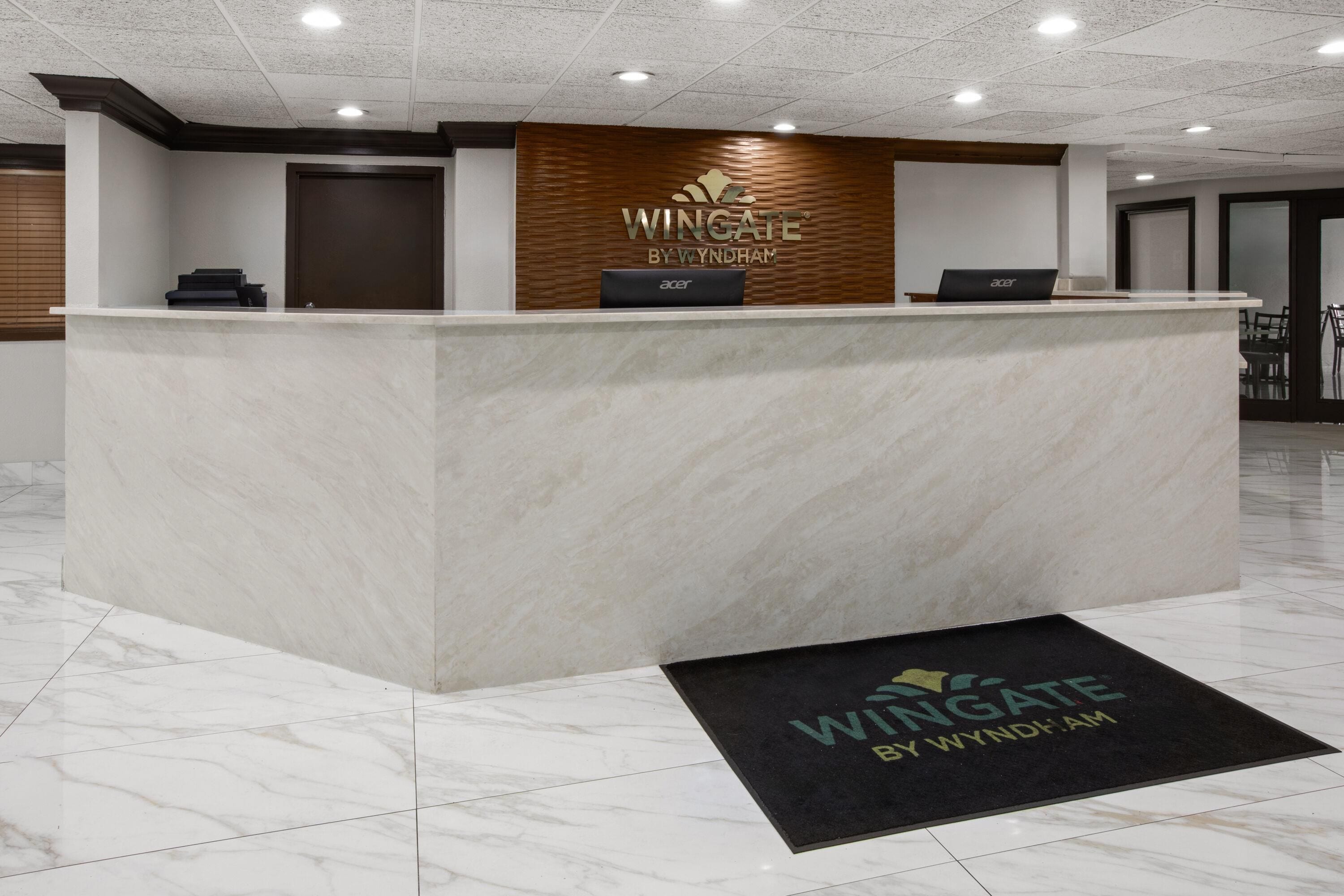 A reception desk with a logo, a door, and a laptop.