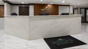 A reception desk with a logo, a door, and a laptop.