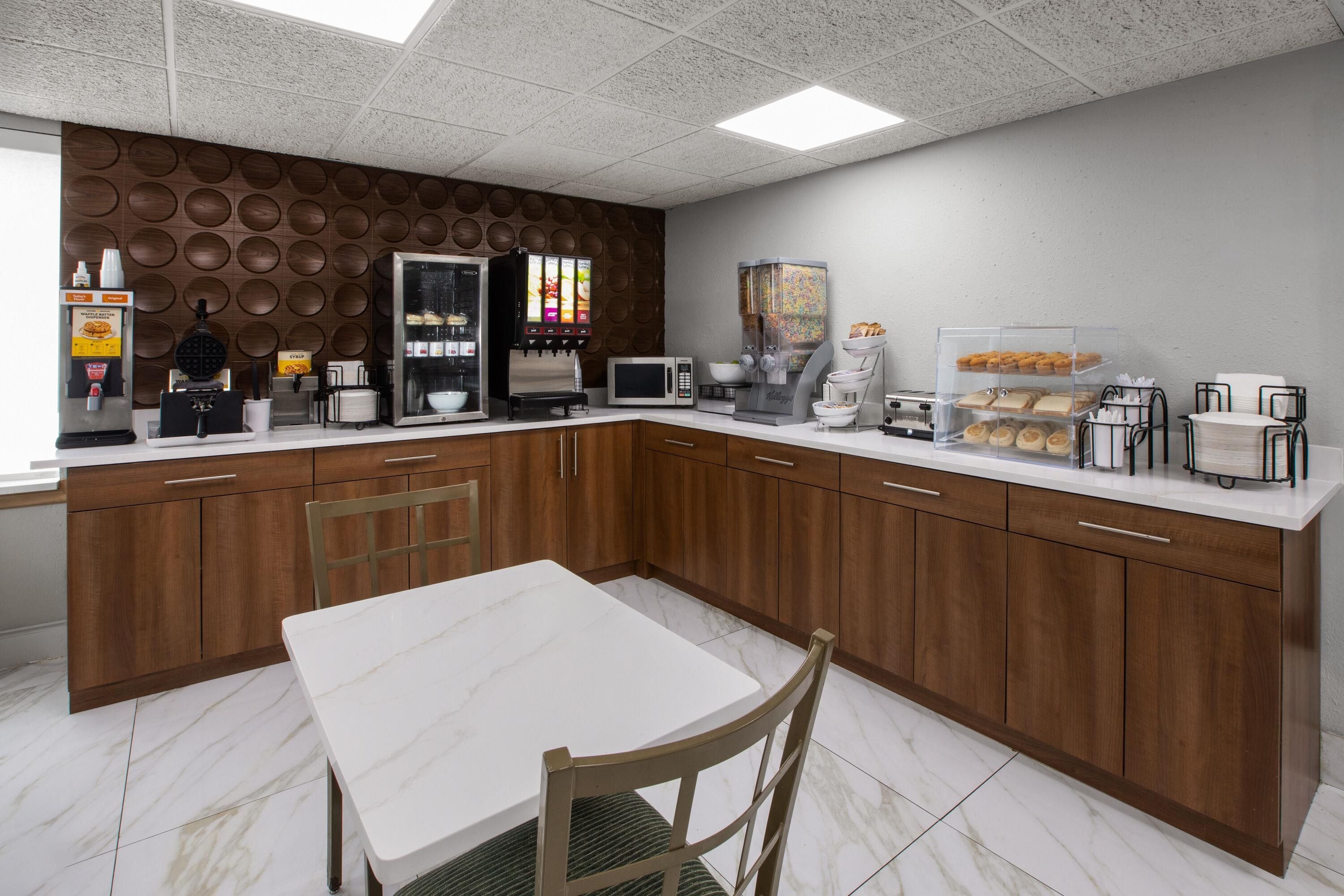 Une cuisine moderne dotée d’un plan de travail en marbre blanc, de meubles en bois et d’un îlot central avec des sièges.