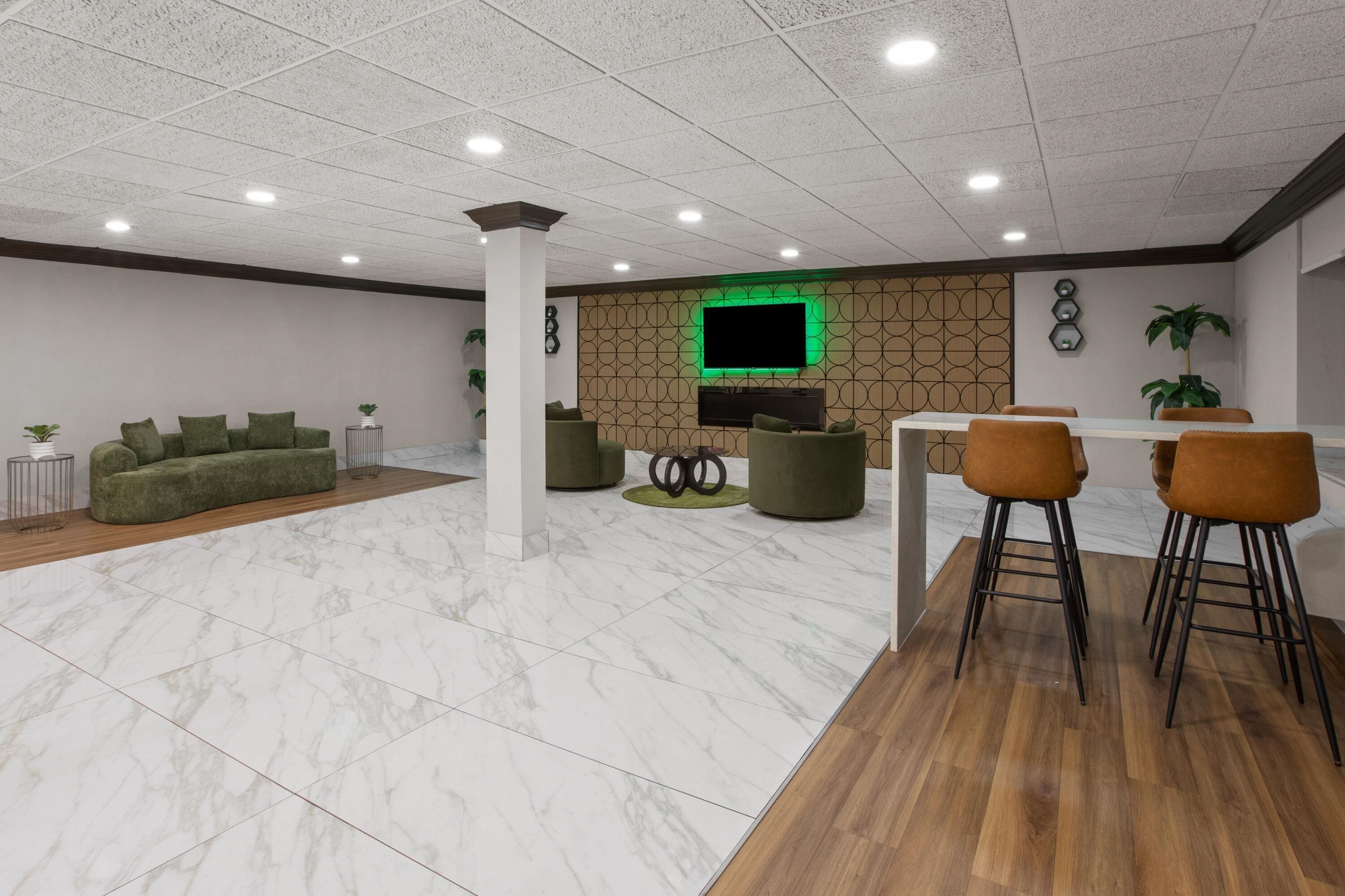 A modern interior with a seating area, a dining space, and a flat-screen TV mounted on a patterned wall.