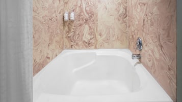 A bathroom with a white bathtub, marble-patterned walls, and a showerhead.