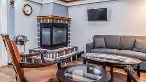 Un salon avec une cheminée, un canapé, une table basse et un téléviseur fixé au mur.