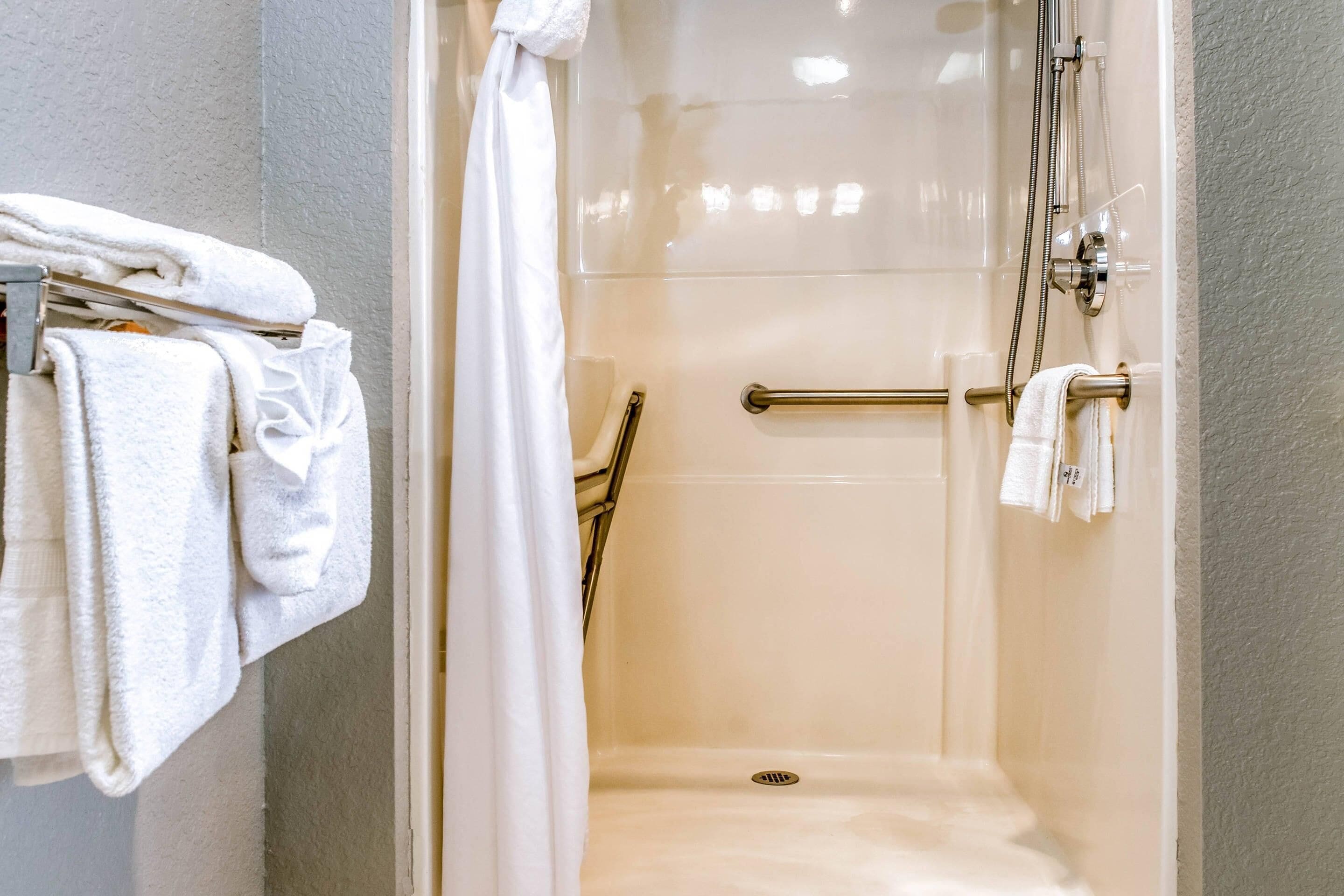 Un baño moderno con cabina de ducha de vidrio, un perchero con toallas dobladas y un pasamanos.