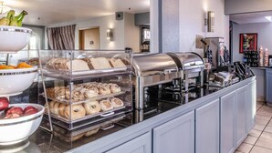 Un buffet pour le petit-déjeuner avec un assortiment de viennoiseries, un coin café et un saladier rempli de fruits.