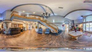 Un intérieur spacieux avec un plancher en bois incurvé, un escalier central et un lustre.