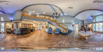 Un interior espacioso con suelo de madera curvada, una escalera central y un candelabro.