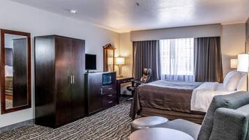 Una habitación de hotel con cama, escritorio con computadora, armario, televisor y zona de estar con mesa y sillas.