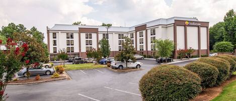 A hotel with a parking lot, multiple buildings, and well-maintained landscaping.