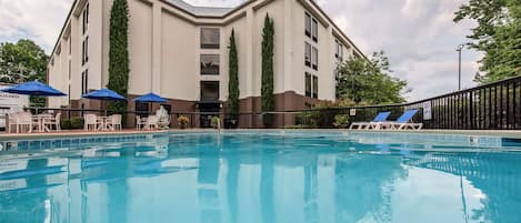 Una piscina al aire libre de temporada, sombrillas