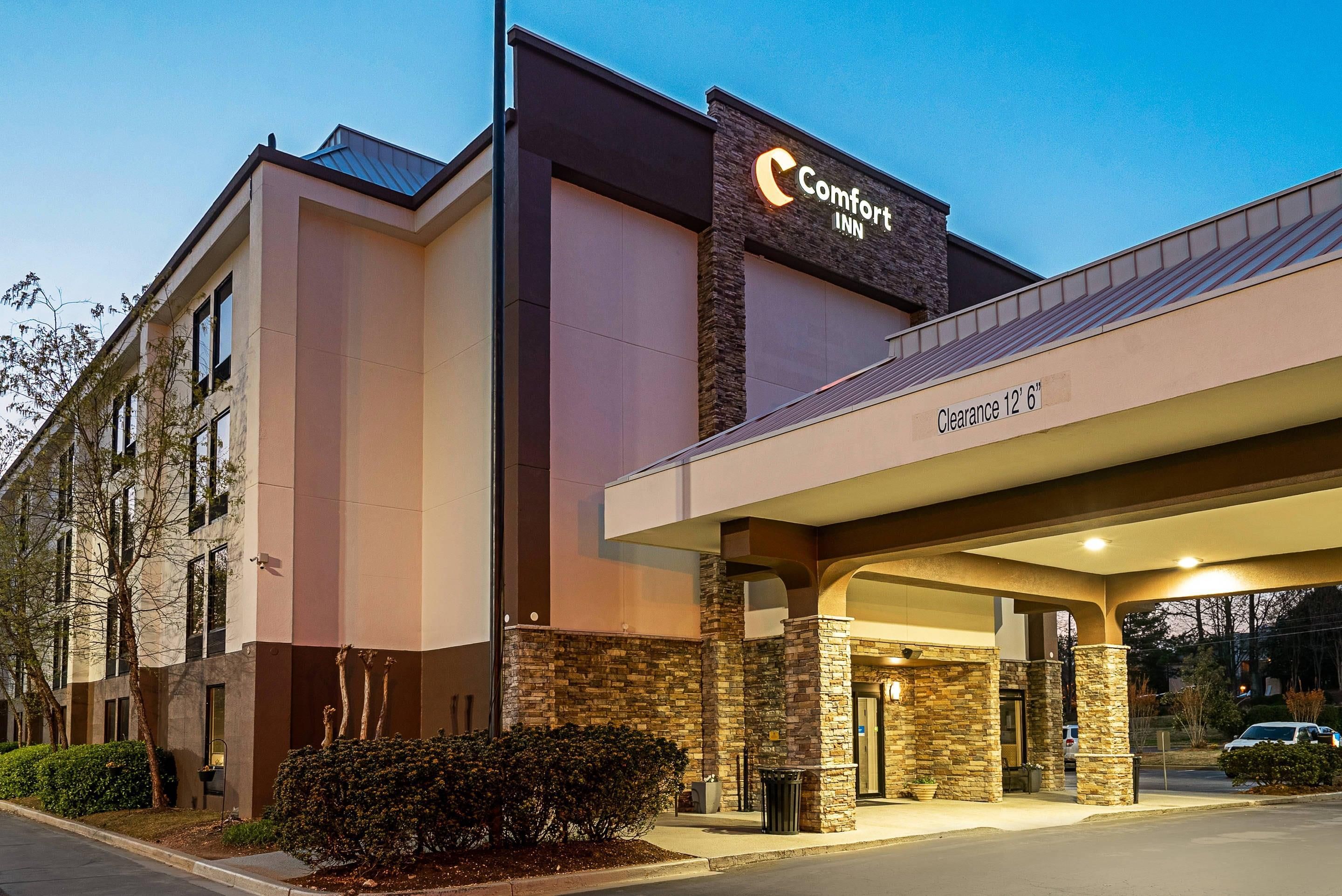 A Comfort Inn hotel with a stone facade, a clear sign indicating a 12'6" clearance, and a well-lit entrance.