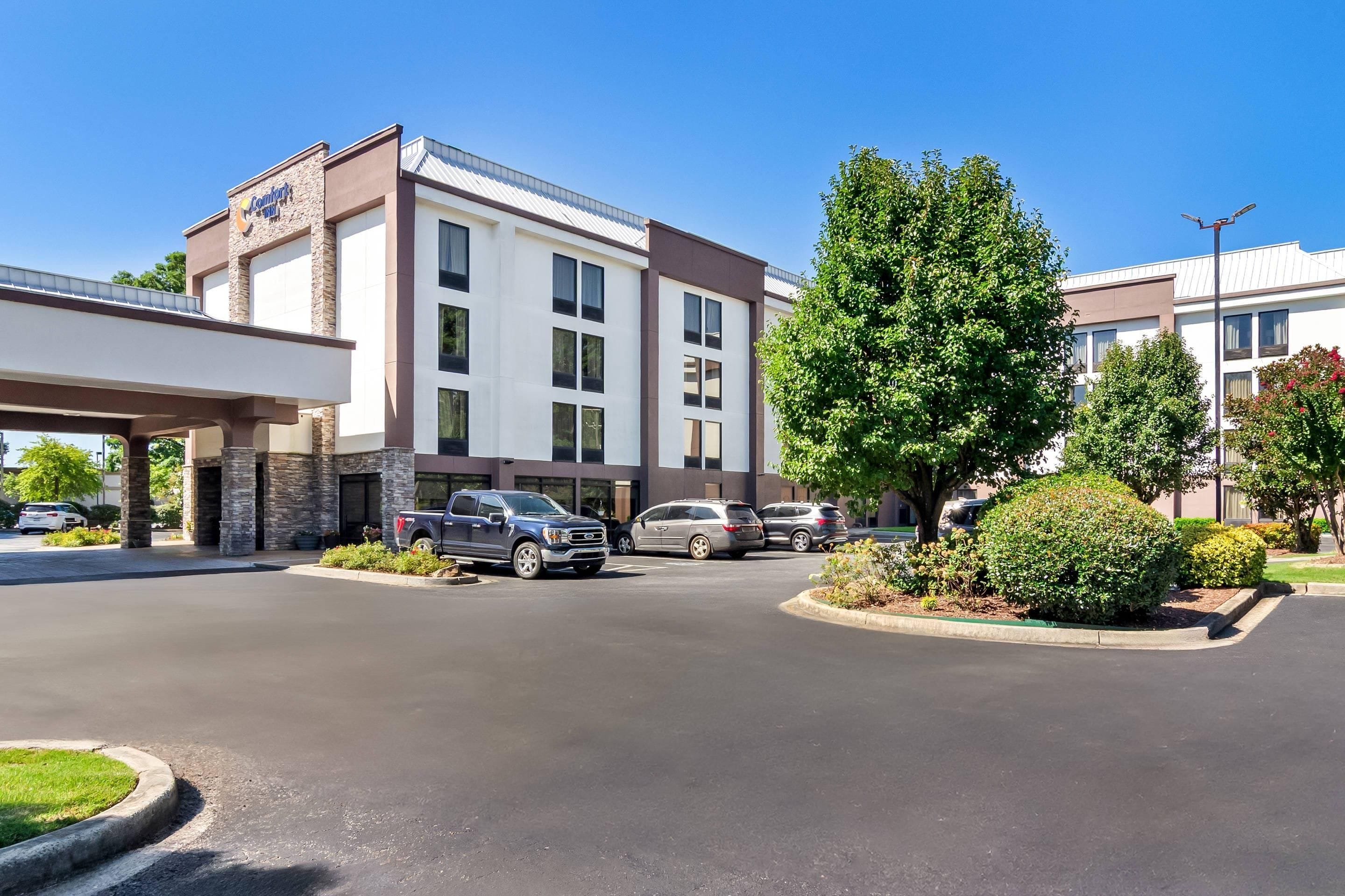 A hotel with a modern design, featuring a large parking lot and a covered entrance.