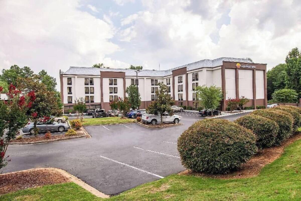 A hotel with a parking lot, multiple buildings, and greenery.