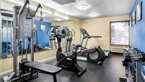 Un gimnasio con máquinas de cardio, pesas y una banca.