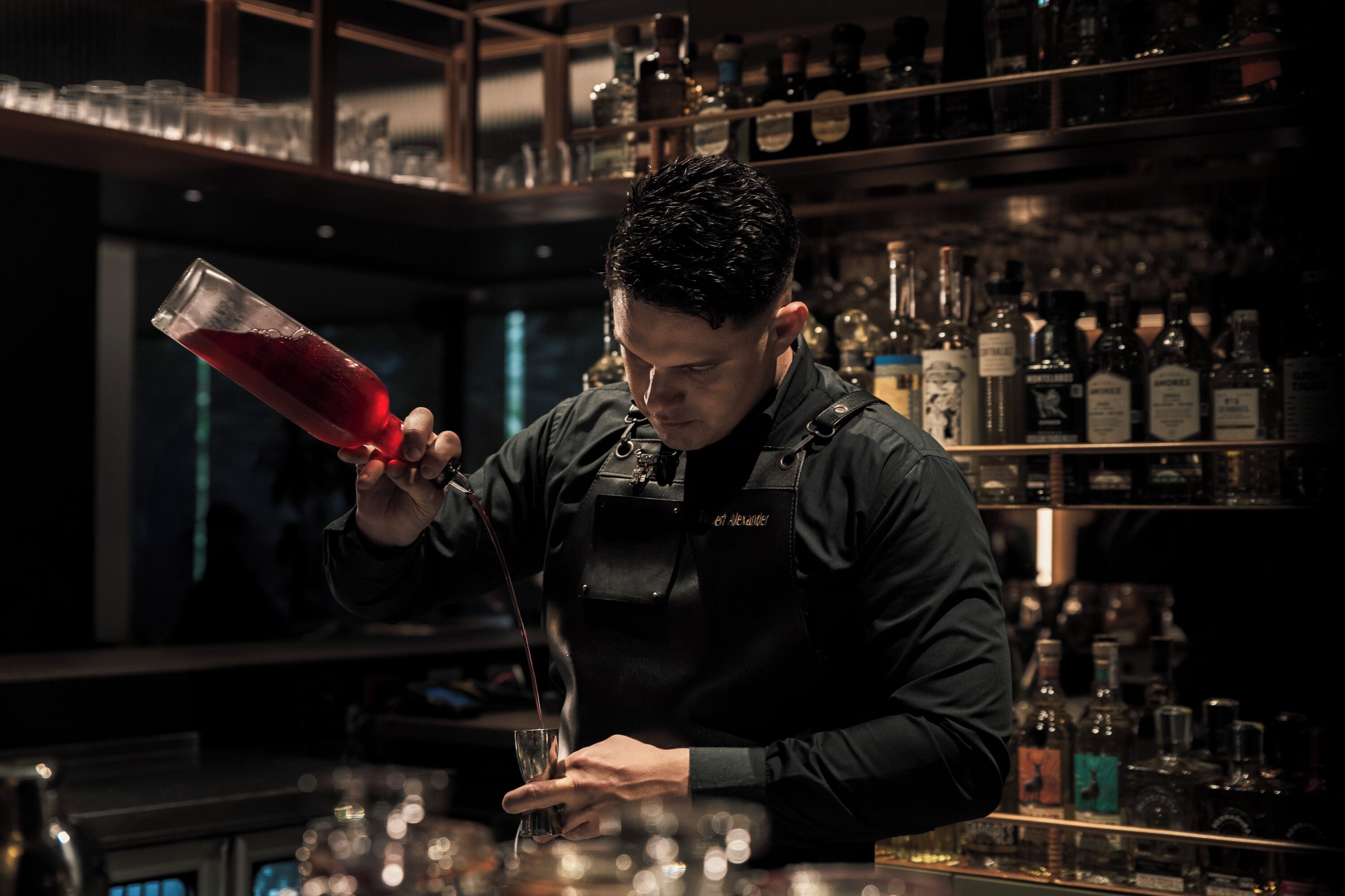 Een bartender giet een drankje in.
