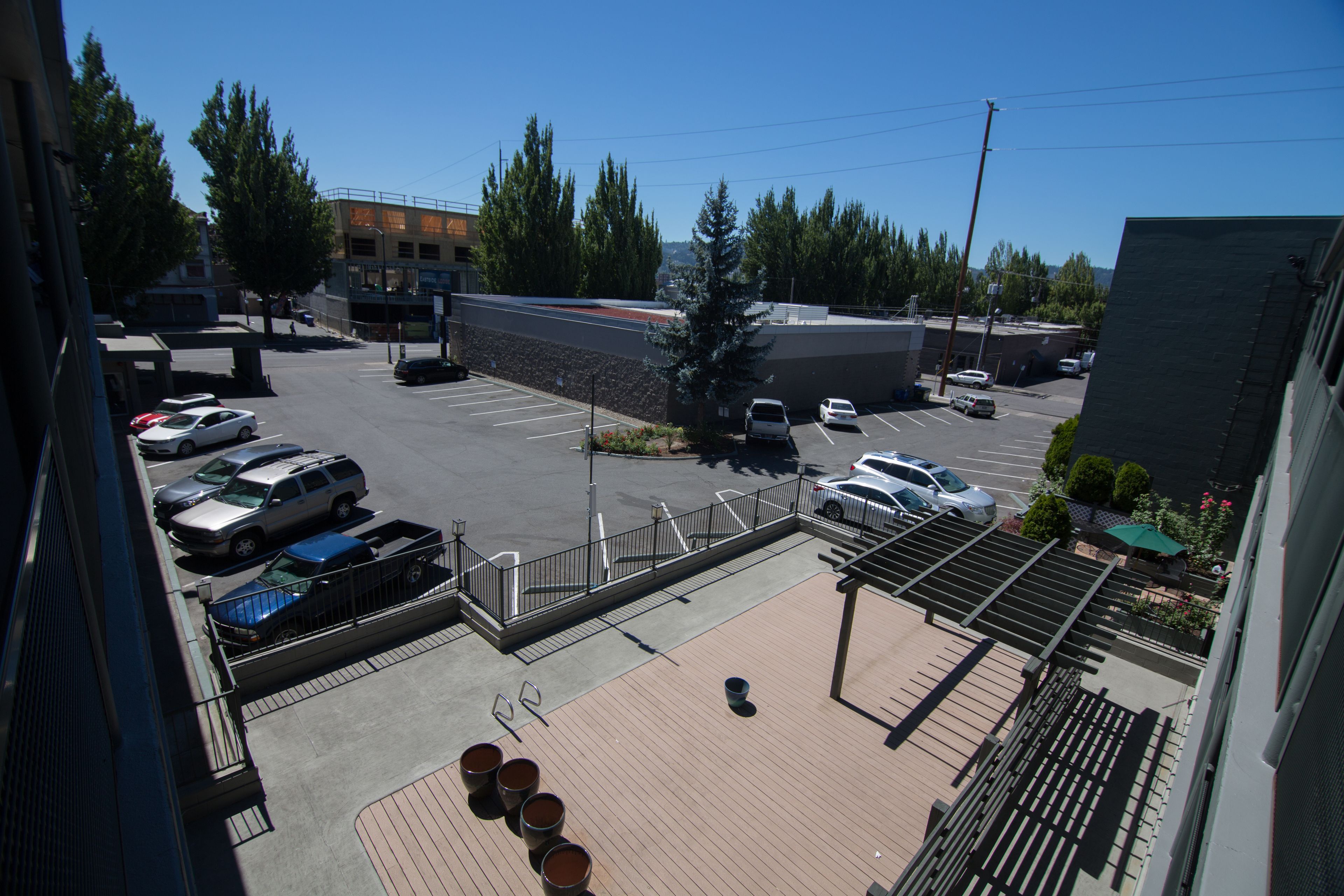 Un estacionamiento con varios coches, un edificio de techo inclinado y un cielo azul despejado.