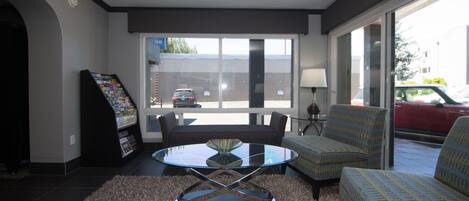 Un salón moderno con una mesa de centro de vidrio, dos sillones estampados, un sofá y suelo alfombrado.