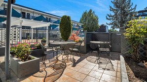 A patio area with outdoor seating, a pergola, and a view of a building with balconies.