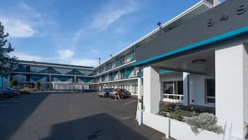 A motel with a parking lot, a building with a blue and white color scheme, and a sign with the number 945.