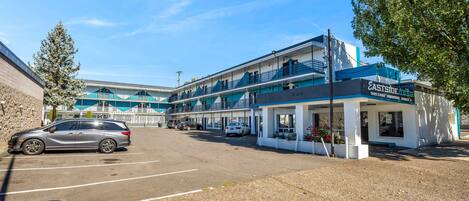 A motel with multiple floors, a parking lot, and a small shop on the ground floor.