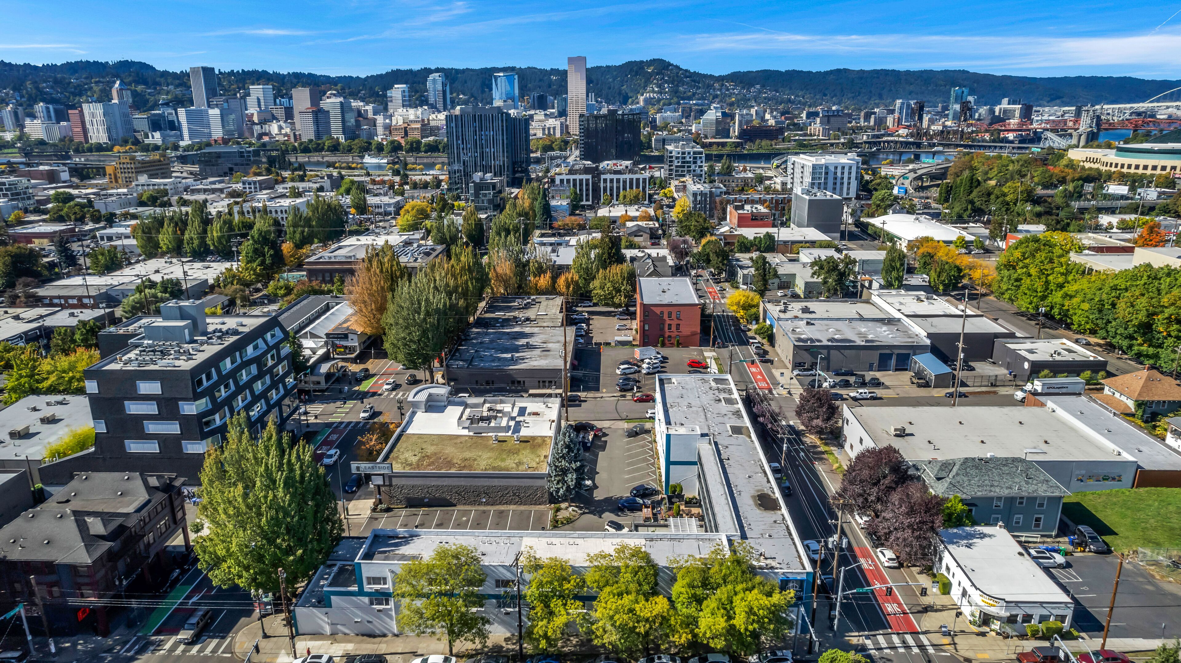 An aerial view of a cityscape with a mix of modern and older buildings, a river, and a hilly backdrop.