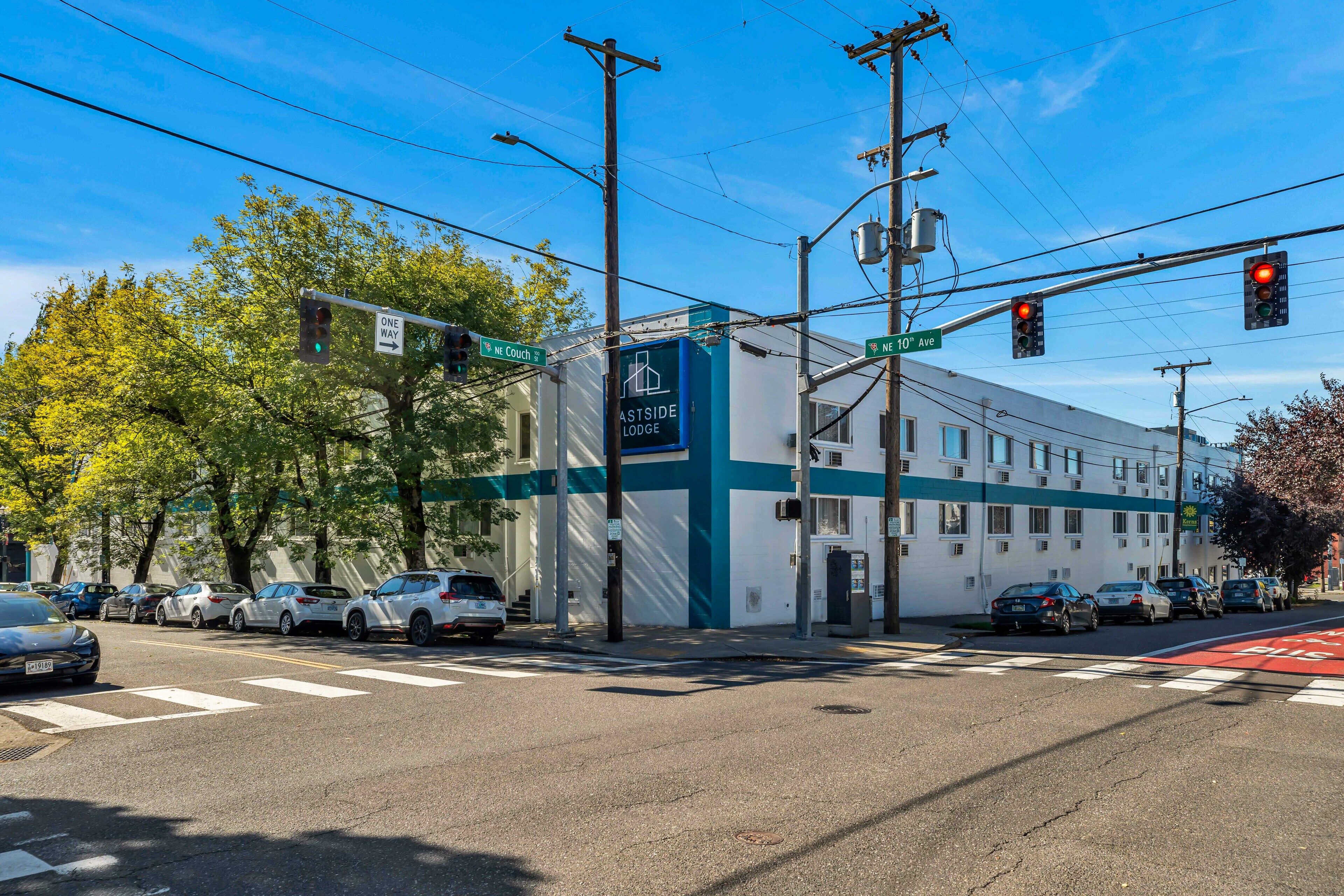Un edificio con un letrero que dice "Astside Lodge" en una esquina de calle con semáforos y coches estacionados.