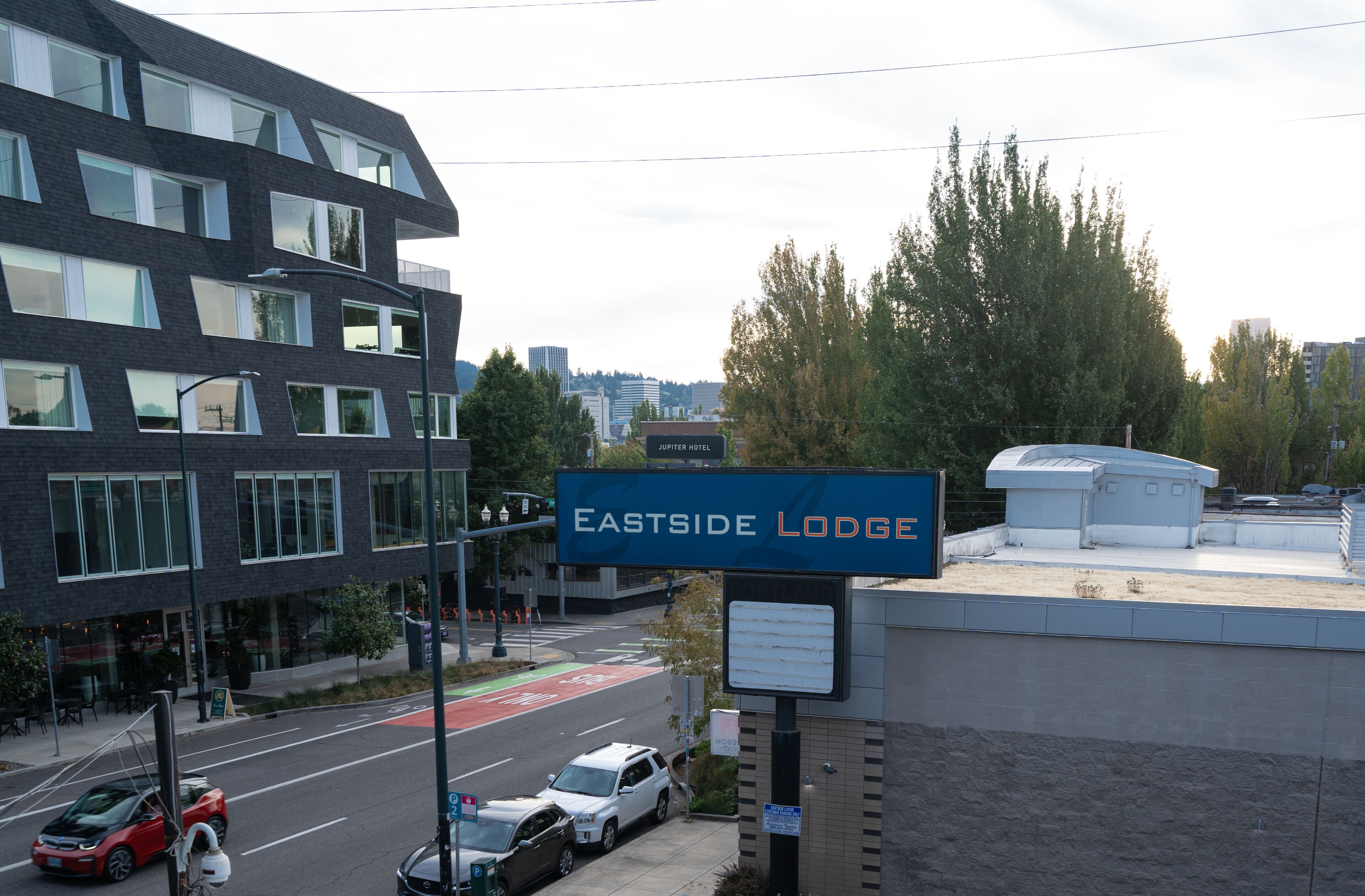 A sign for Eastside Lodge with a modern building in the background.