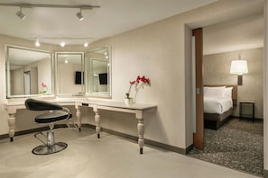 A hotel room with a large mirror, a desk, a chair, a bed, and a nightstand with a lamp. - Hilton Garden Inn Springfield (Springfield)