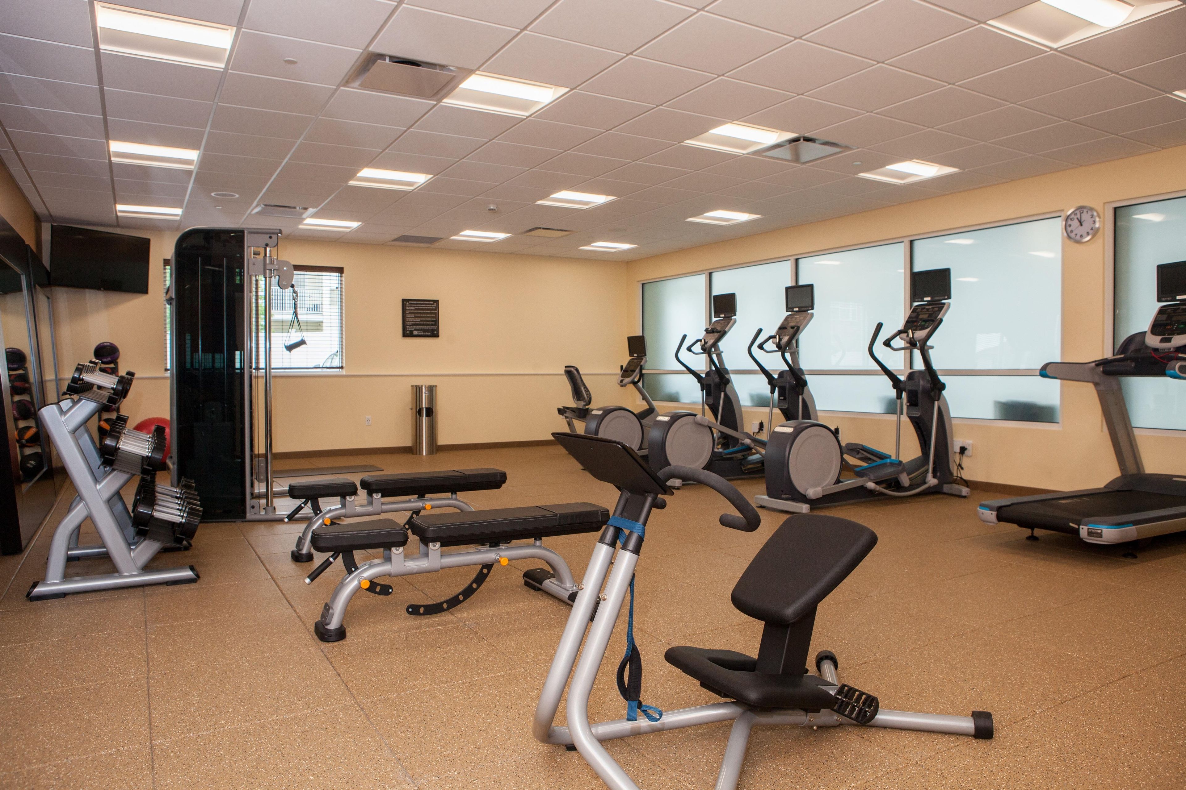 Un gimnasio con diversos equipos de ejercicio, incluyendo cintas de correr, bicicletas estáticas y máquinas de pesas.