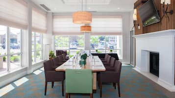 A conference room with a long table, chairs, a fireplace, and large windows.