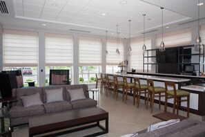 A modern kitchen with a bar area, seating, and large windows. - Hilton Garden Inn Springfield (Springfield)