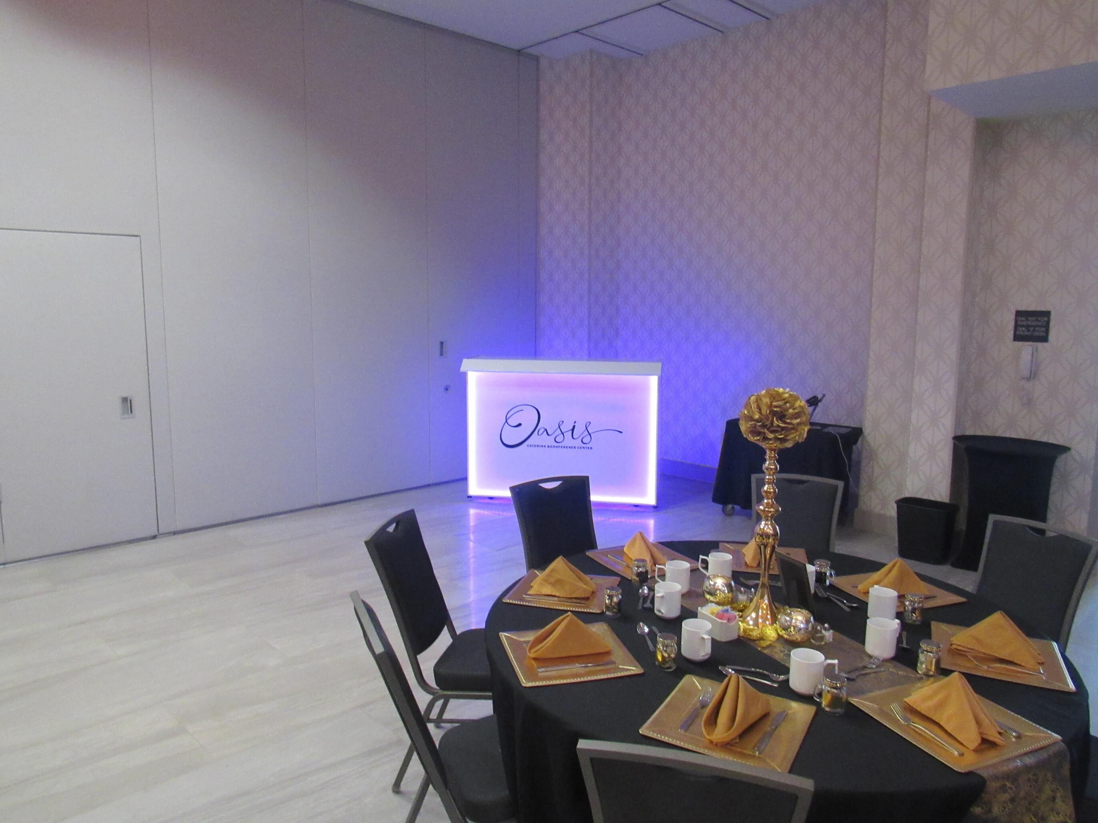 A conference room with a podium labeled 'Oasis' and tables set for a meeting.