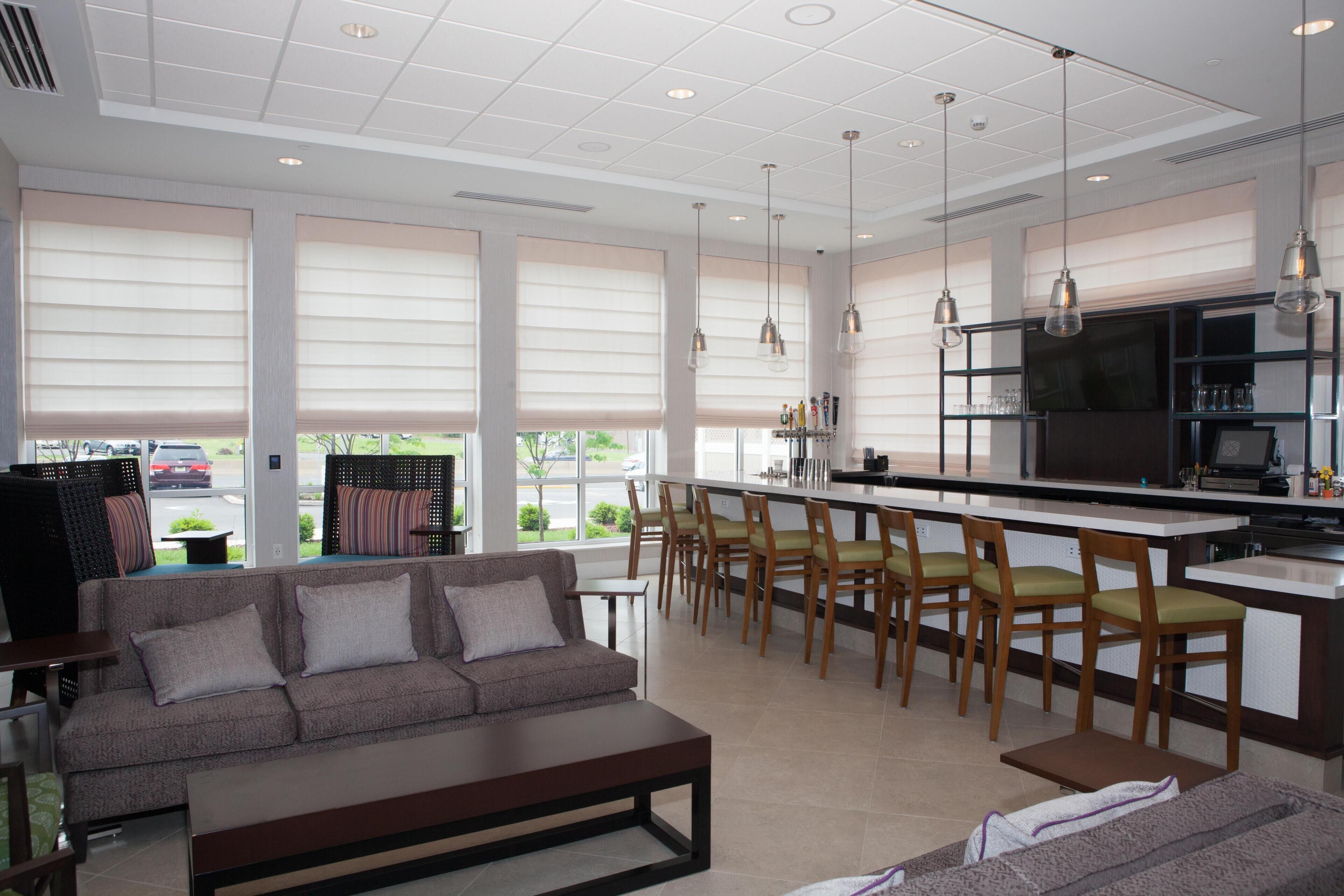 A modern kitchen with a bar area, seating, and large windows.