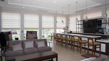 A modern kitchen with a bar area, seating, and large windows.
