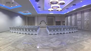 A conference room with rows of white chairs, a decorative arch, and modern lighting fixtures.