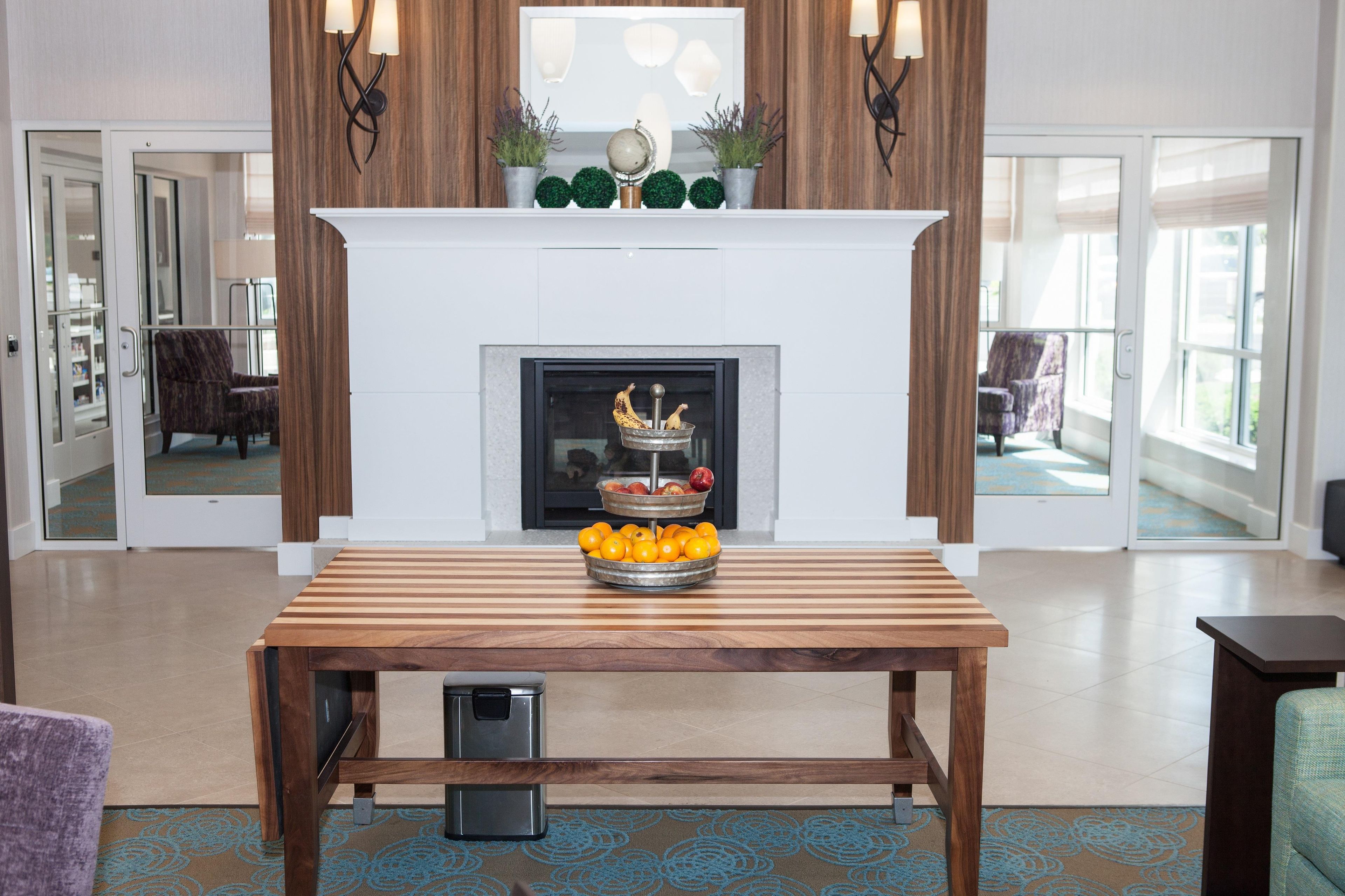 Una sala de estar moderna con chimenea, una mesa de madera con fruta y un televisor.