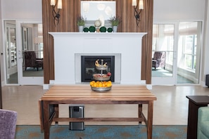 Una sala de estar moderna con chimenea, una mesa de madera con fruta y un televisor.