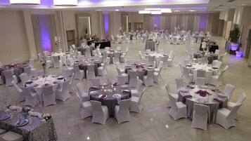 A large banquet hall with round tables, white chairs, and purple accents.