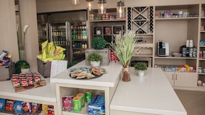 A well-organized snack bar with various packaged snacks, a refrigerator stocked with beverages, and a coffee machine.