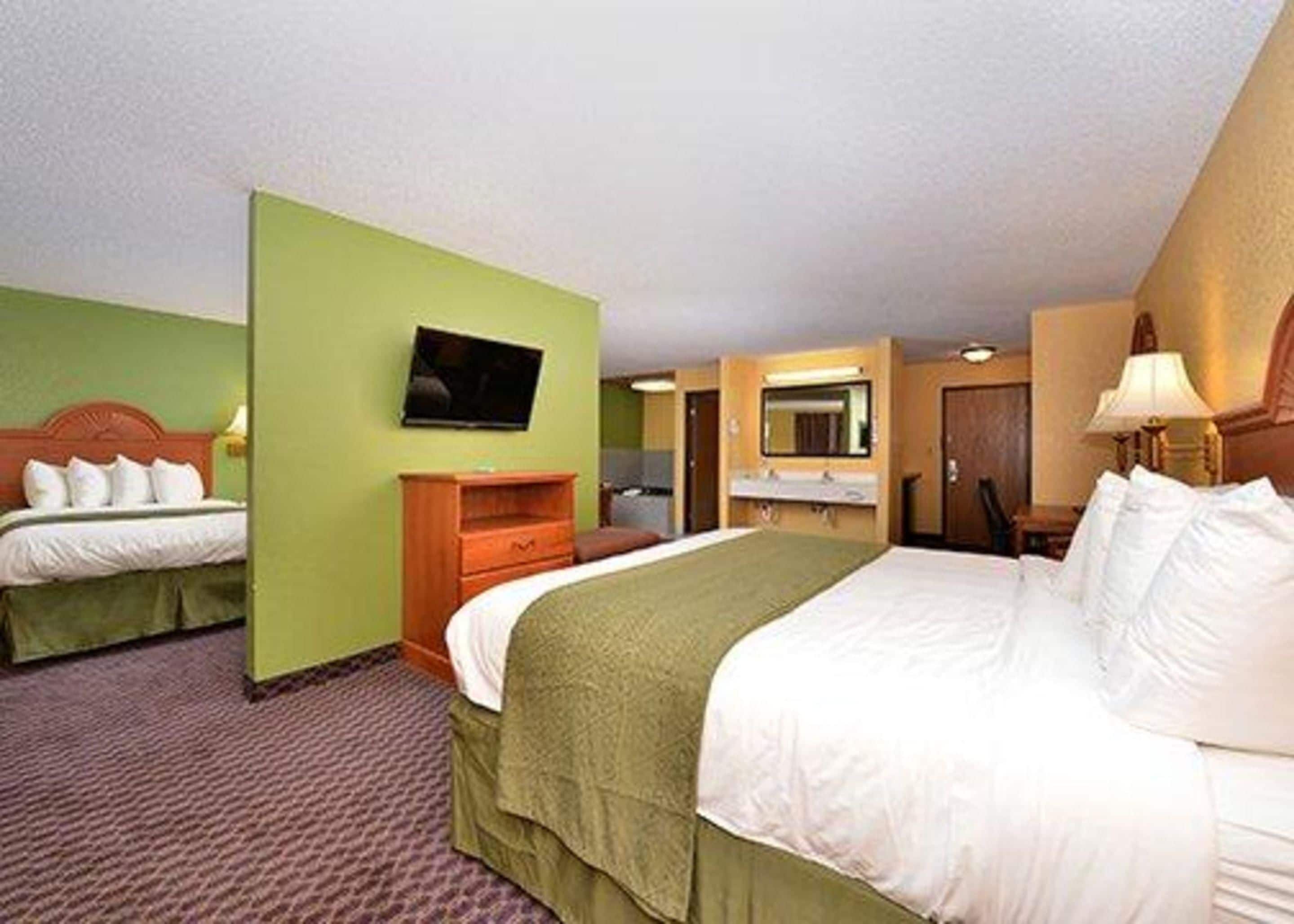 Habitación de hotel con dos camas, televisión, escritorio y espejo.